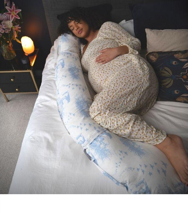 Pregnant woman relaxing in comfort on bed with full body xxl u shaped pregnancy pillow. Large pregnancy pillow helps pelvic girdle pain. Pregnancy pillow allows you to get sleep. Supports your bump. Sleeping in final trimester. Nice looking pregnancy pillow. Best pregnancy pillow UK. BellaMoon Pregnancy and Nursing Pillow